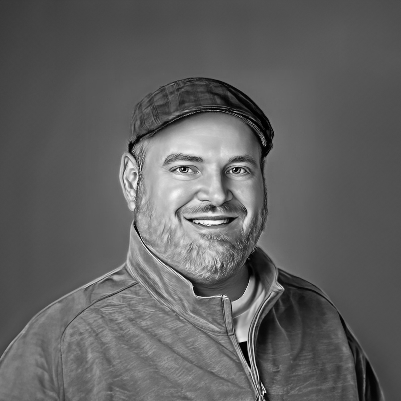 Denny Basham, smiling CEO of Tech Marketing Team, wearing a cap and casual jacket, representing leadership in digital marketing strategies.